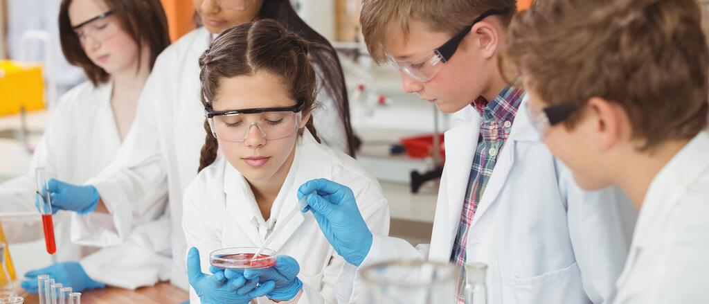 Schülerinnen und Schüler in Labormänteln nehmen Proben. Schülerinnen und Schüler in Labormänteln nehmen Proben.