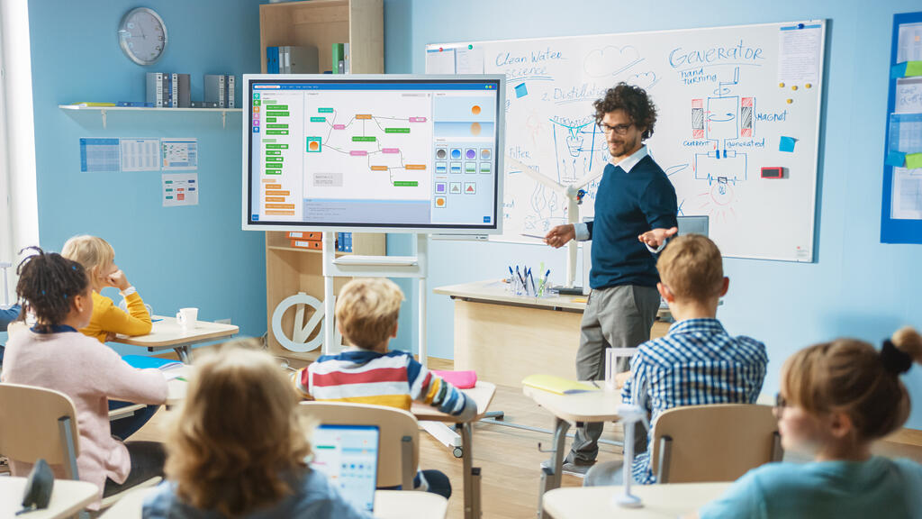 Unterricht im digitalen Klassenzimmer Ein Lehrer unterrichtet seine Klasse mit Hilfe eines digitalen Whiteboards.