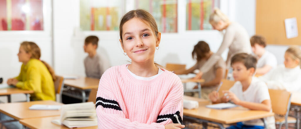 Startchancen Ein Mädchen steht im Bildfokus im Klassenzimmer